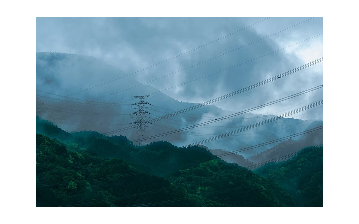 Power transmission corridor crosses forested hills.