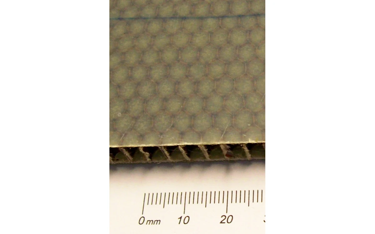 Honeycomb sandwich panel showing facesheet and cellular core at its cut edge.